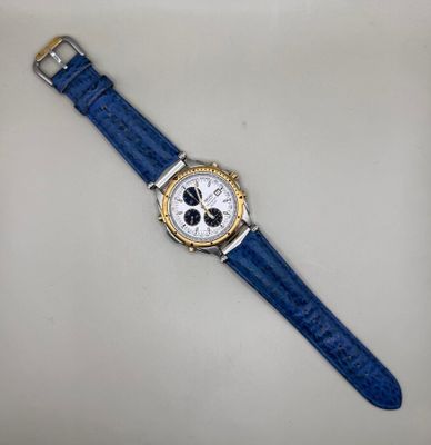 gros plan d'une montre sur une surface blanche avec un bracelet bleu