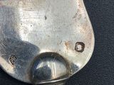 a silver spoon with a hole in it on a black surface