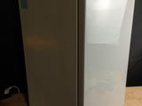 a white refrigerator sitting on a wooden table in front of a black wall