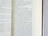 someone is reading a book on a table with a pencil in their hand