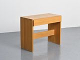 a small wooden bench in a room with a white wall