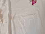 white t - shirt with a pink heart embroidered on the chest