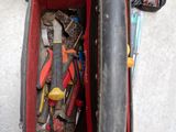 une valise rouge posée par terre, contenant des outils