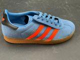 blue and orange adidas sneakers with gum soles on a gray surface