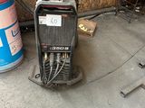 an image of a welding machine sitting on the ground next to a can of soda