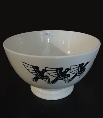 a white bowl with black designs on it on a black table
