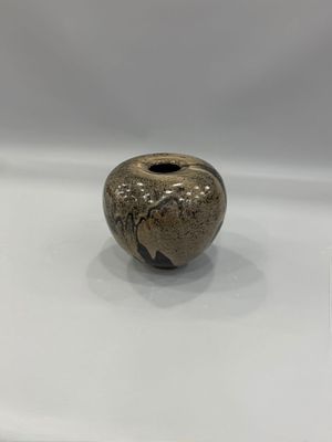 un petit vase posé sur une surface blanche