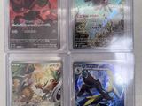 four different pokemon cards in plastic cases sitting on a table