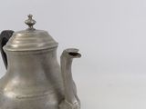 a silver tea pot with a handle on a white surface