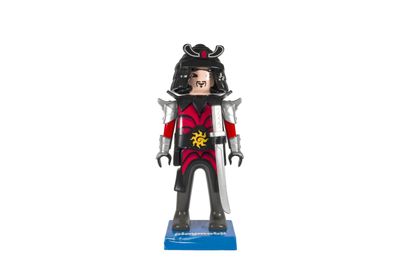La figurine est en métal et porte une tenue rouge et noire.