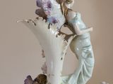 a white vase with a figurine of a woman and children on it