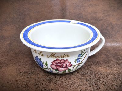 a white bowl with a blue rim on a brown surface