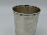 a silver cup with a handle sitting on a white surface