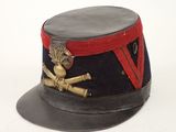 un chapeau noir orné d'un ruban rouge et d'un insigne doré