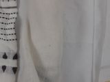 a white sweater hanging on a clothes rack with a tag attached to it