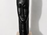 sculpture noire représentant la tête d'une femme, posée sur un socle en marbre
