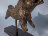 bronze sculpture of a boar on a marble base on a blue background