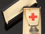 a silver medal in a box with a red cross on it