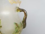 un vase blanc orné de feuilles vertes, posé sur une table