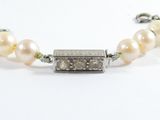 a close up of a white pearl bracelet with a silver clasp