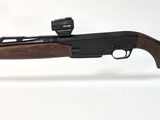 un fusil posé sur un support transparent, sur une surface blanche