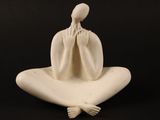 sculpture représentant une femme assise sur un oreiller, les mains sur le visage