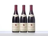 three bottles of red wine are lined up on a table