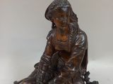a bronze statue of a woman sitting on a rock