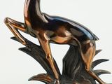 bronze statue of a deer on a leafy base with a white background