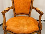 une chaise avec une assise rembourrée orange et un cadre en bois