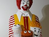 statue of ronald the clown holding a child and a hamburger