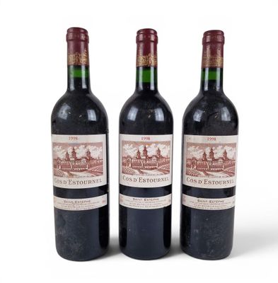 three bottles of red wine sitting next to each other on a white surface