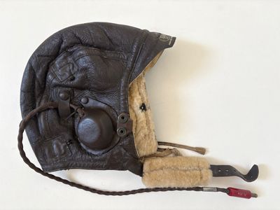 a black leather hat with a brown fur lining and a pair of scissors attached to it