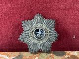 a small silver brooch on a red cushion