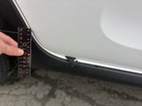 someone is measuring the width of a car door with a ruler