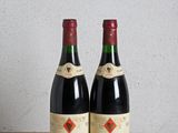 deux bouteilles de vin posées sur une table en bois, à côté d'une bouteille de vin