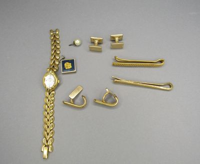 a gold bracelet, a watch, and other jewelry on a table