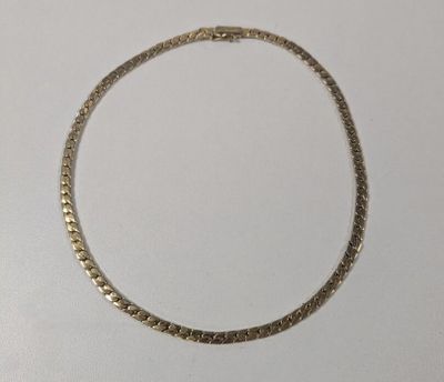 gros plan d'un collier en or sur une surface blanche