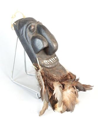 a wooden mask on a stand with feathers on it