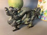 a statue of a dragon on a table next to a vase