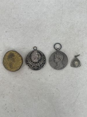 three silver and gold coins and a silver coin on a white surface