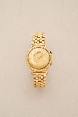 a close up of a gold wrist watch on a white surface