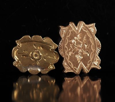 un gros plan sur une paire de broches en or posées sur une surface noire