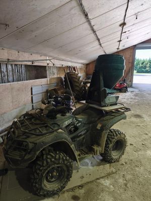 un quad vert garé dans une grange, avec un godet à l'arrière