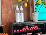 two bottles of makeup sitting on a shelf next to a vase of lemons