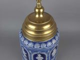 an antique blue and white vase with a gold lid on a gray background