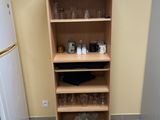 a tall wooden shelf in the corner of a kitchen