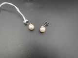 une paire de boucles d'oreilles en perles posées sur une surface noire, avec une étiquette de prix
