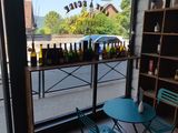 a table and chairs in front of a window with bottles of wine on it