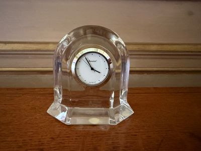 a clear clock sitting on top of a wooden table